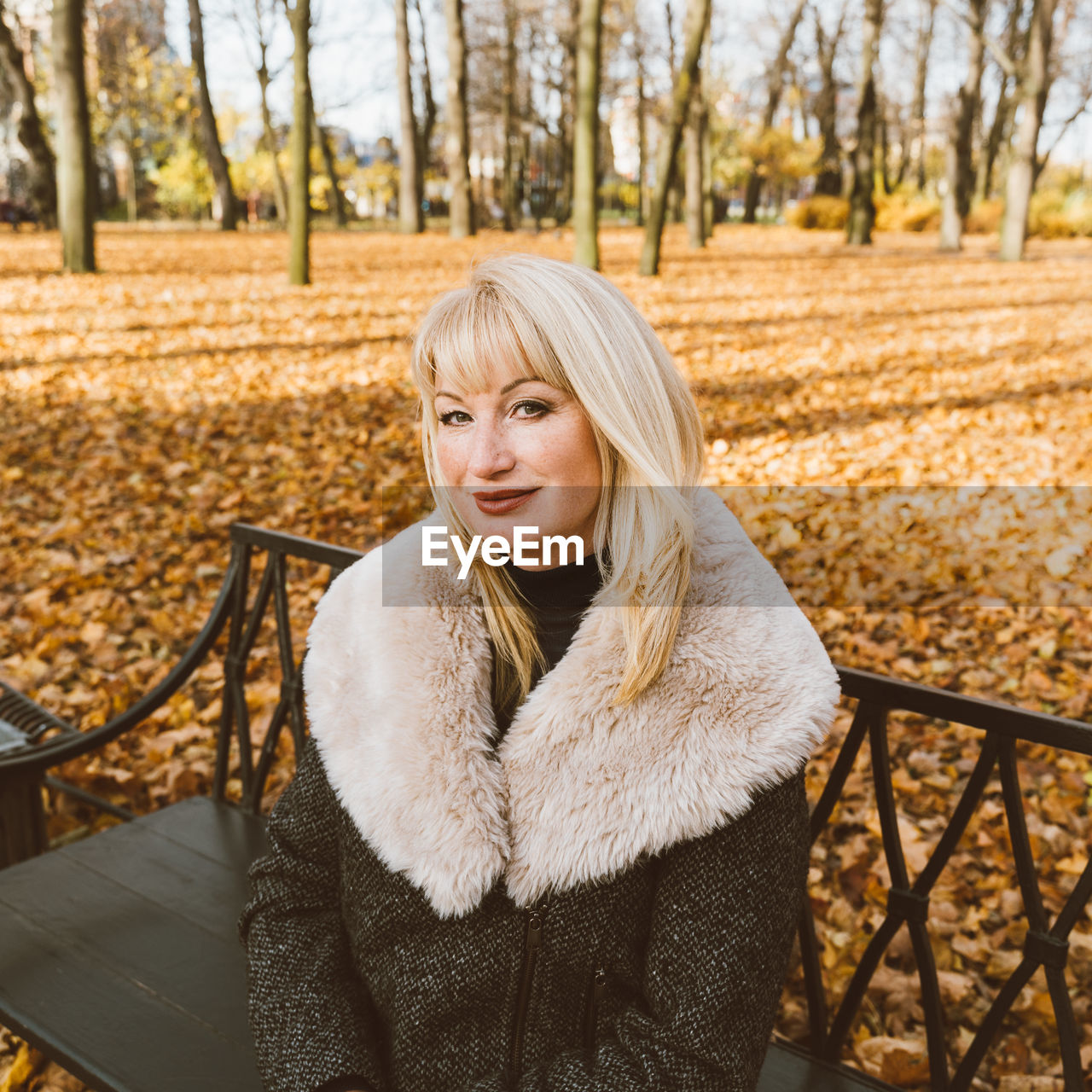 Portrait of woman sitting on bench in park