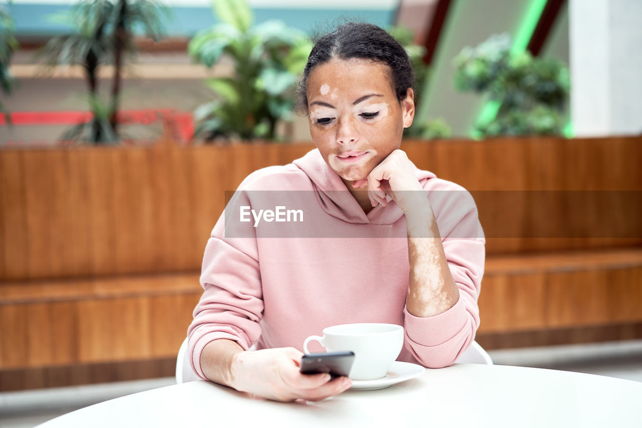 Man using mobile phone while sitting on table