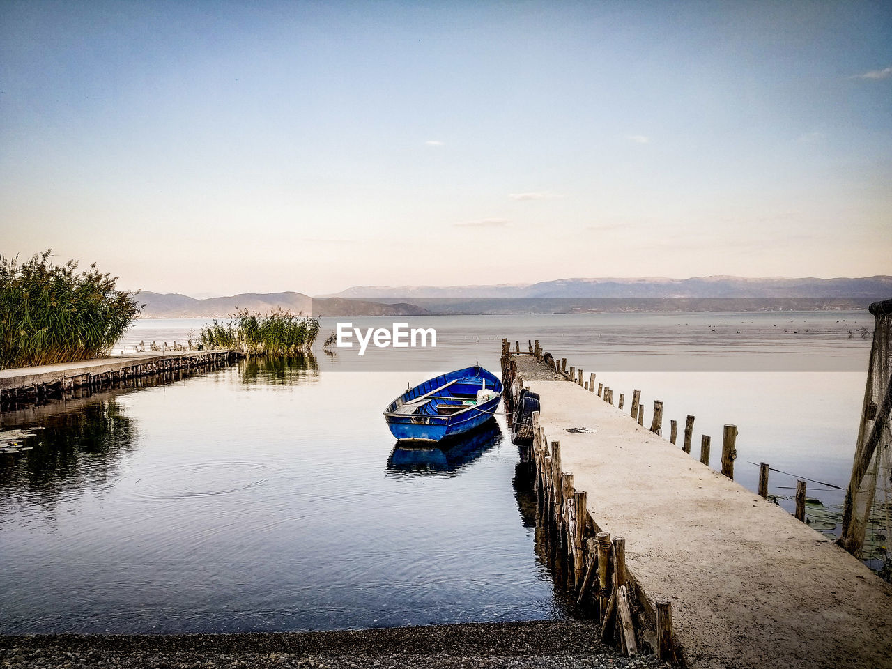 Scenic view of sea against clear sky with fishing boat at sunset