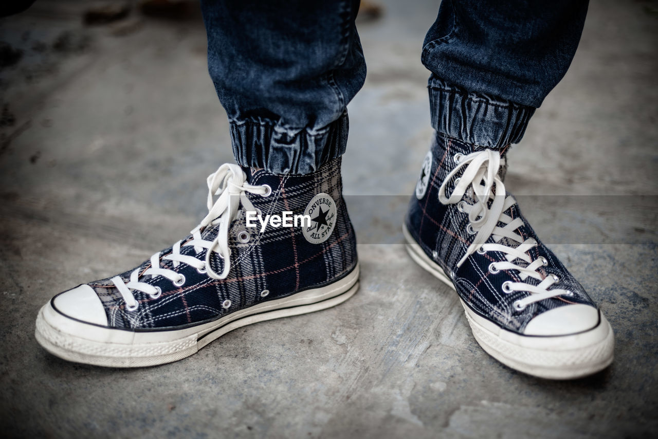 LOW SECTION OF PERSON WEARING CANVAS SHOES STANDING