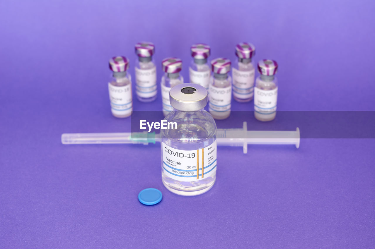 Vaccine, covid-19 coronavirus hand holding vaccine on purple background	