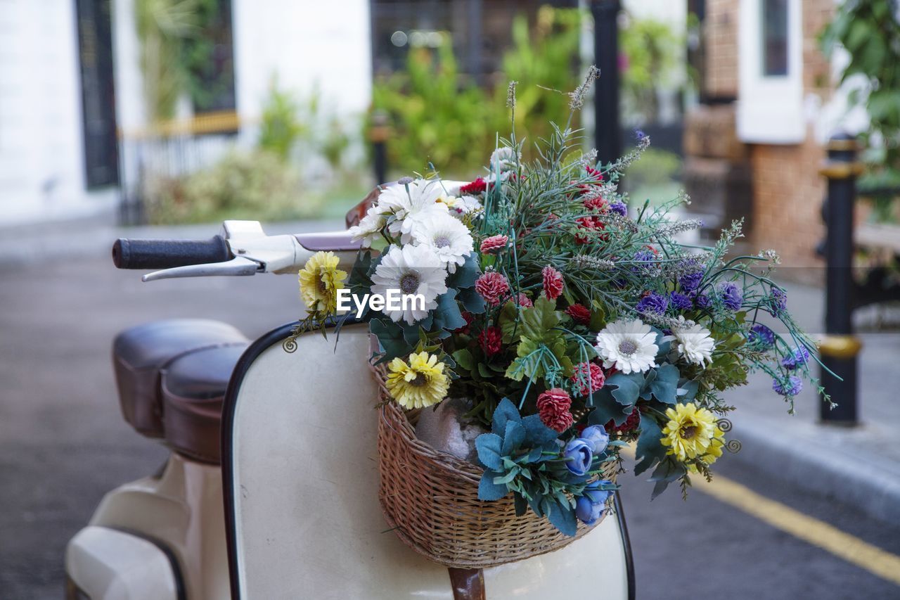 Bouquet of flower on scooter. close-up of flower pot on street