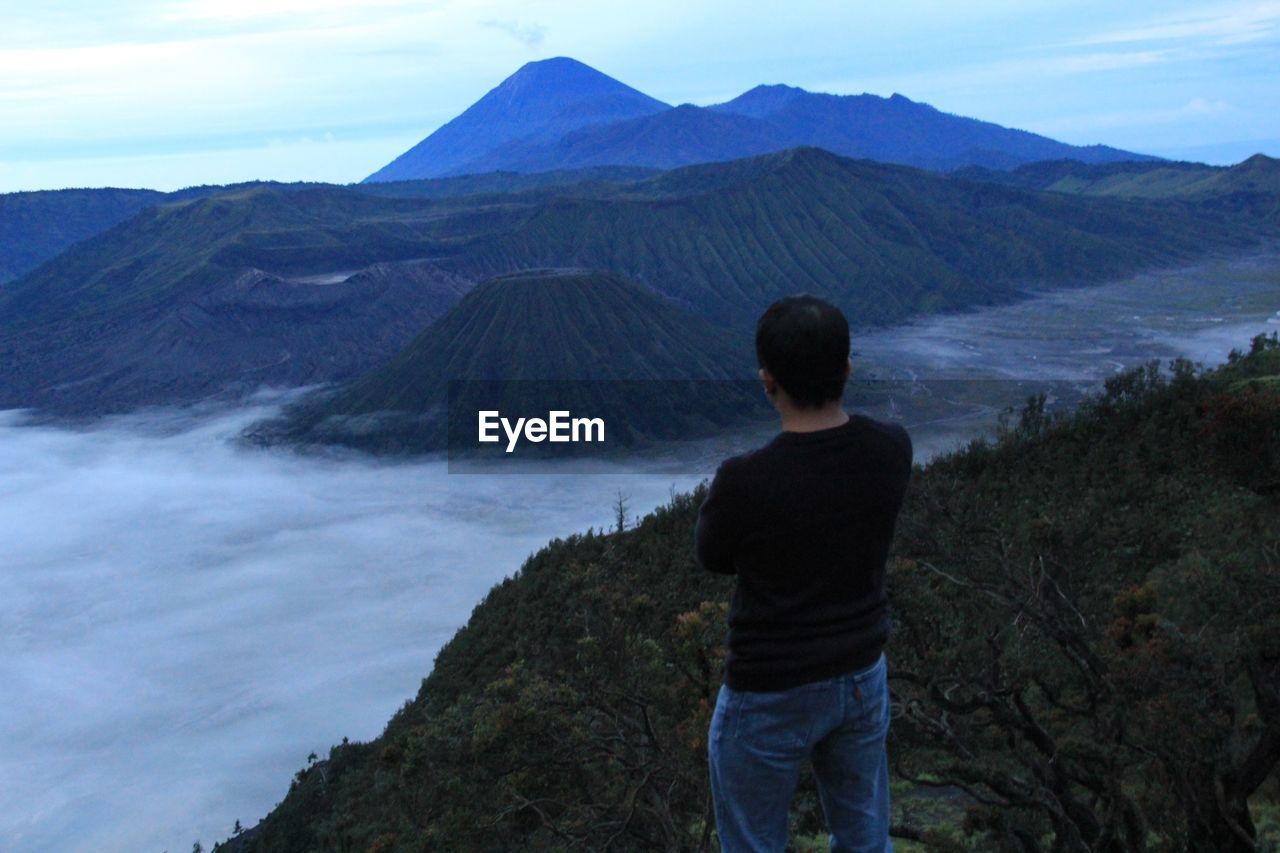 MAN STANDING ON MOUNTAIN