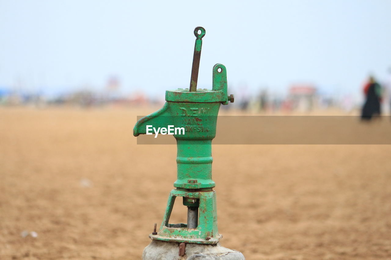 Green water pump on field against sky