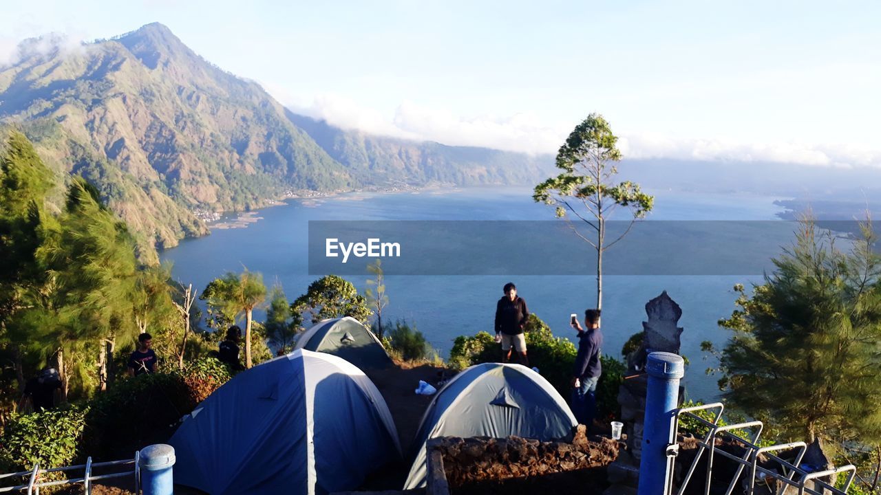 Panoramic view of tent on mountain by lake against sky