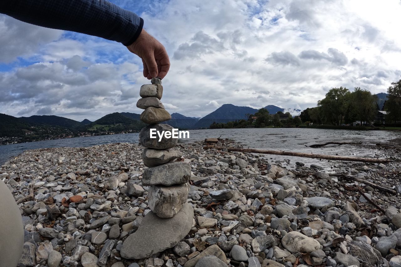 Hand holding stone while stacking stones pyramid