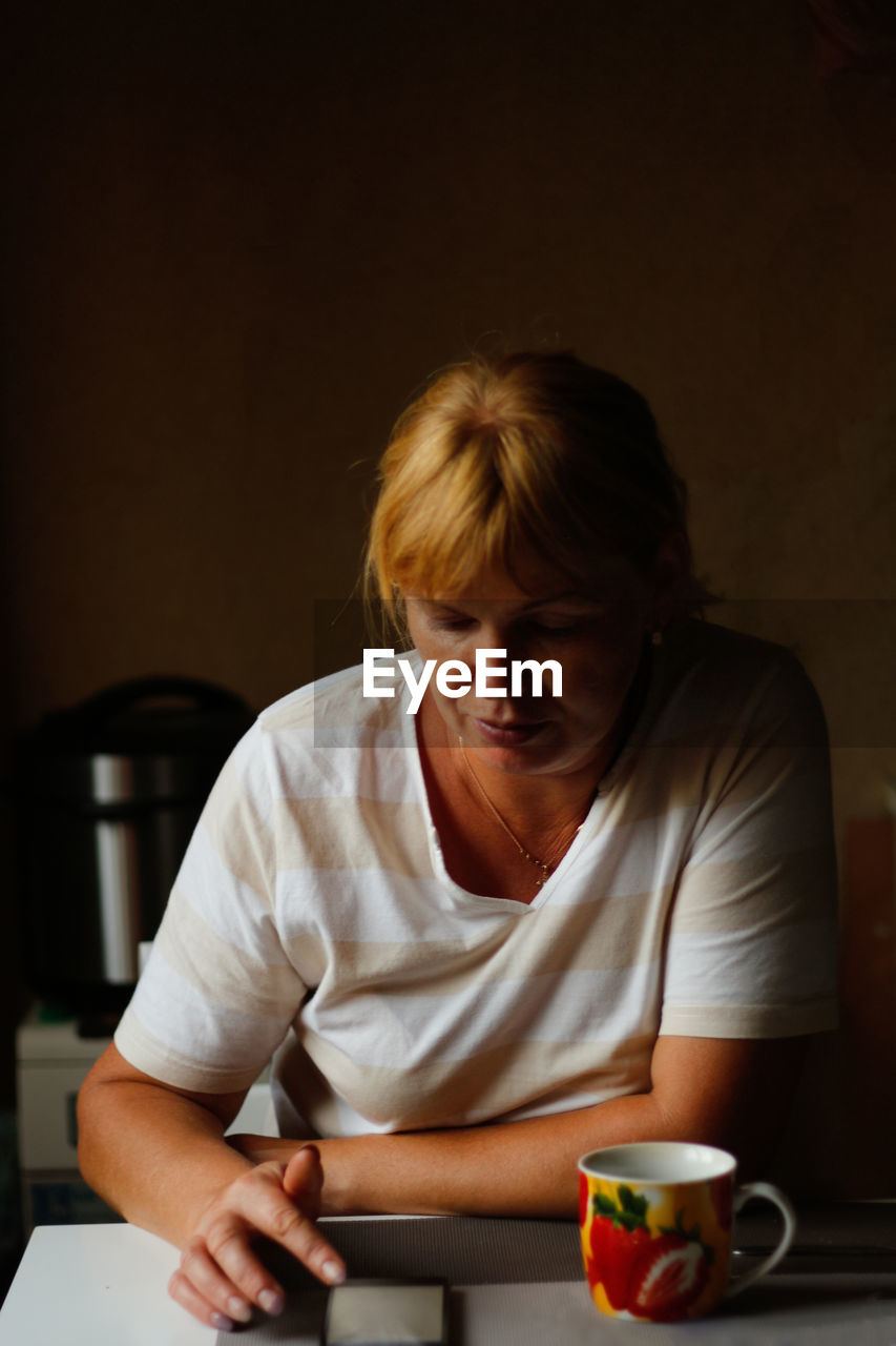 Happy young caucasian woman using mobile phone while sitting at home with coffee or tea mug. morning