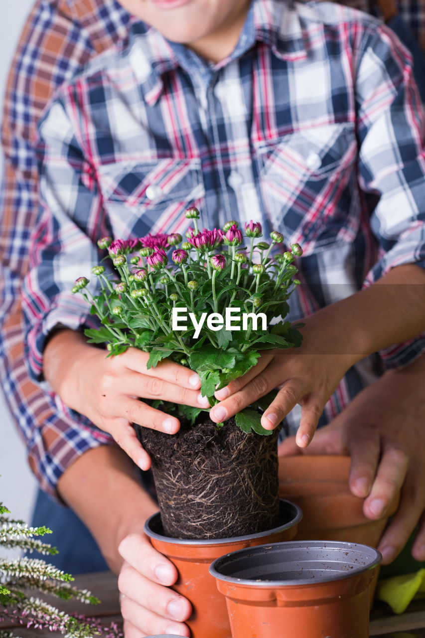 Midsection of boy potting plant