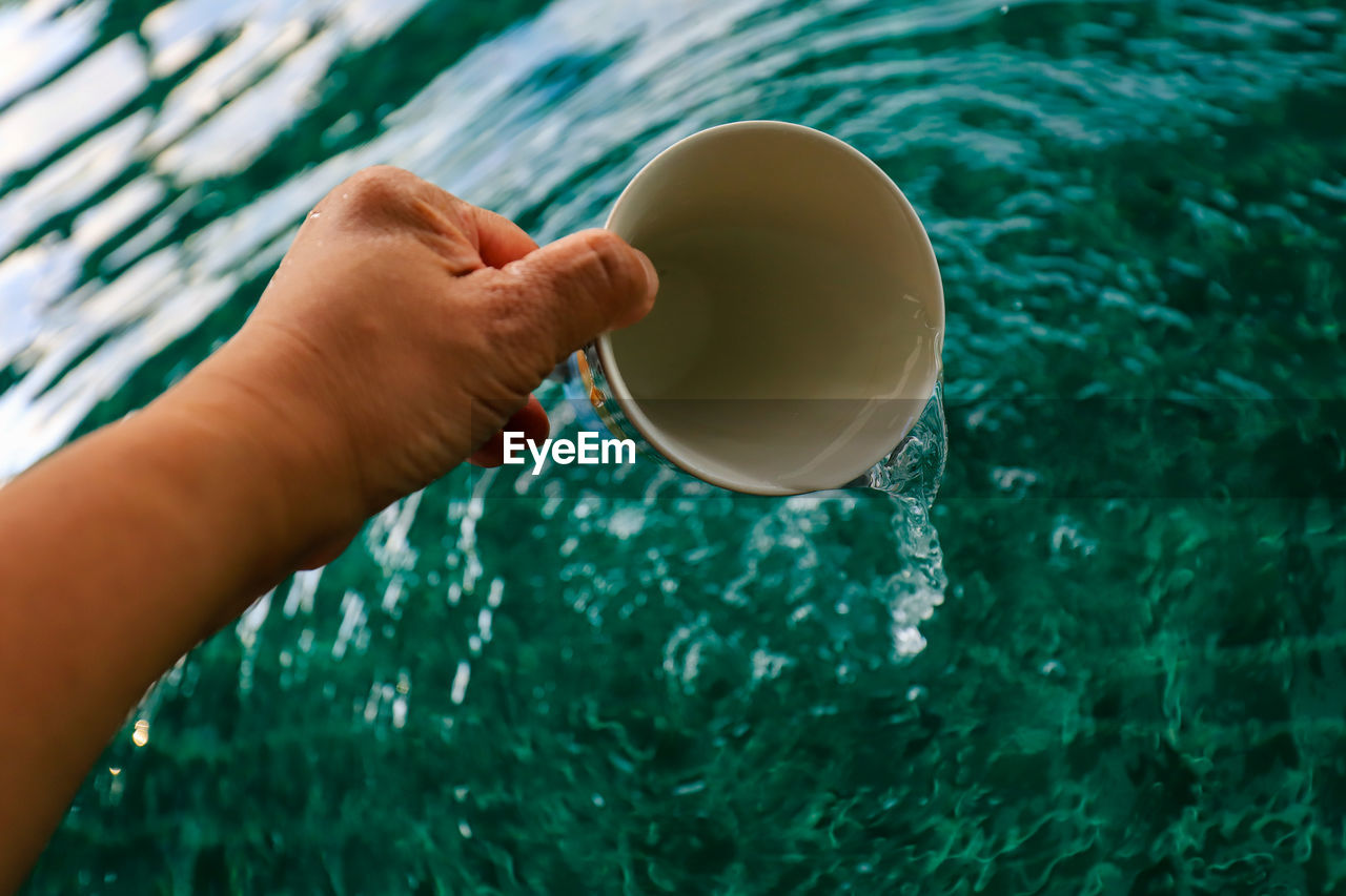 High angle view of hand holding coffee cup in swimming pool