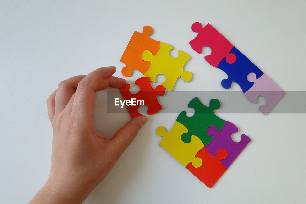 Close-up of hand holding puzzle piece over flooring