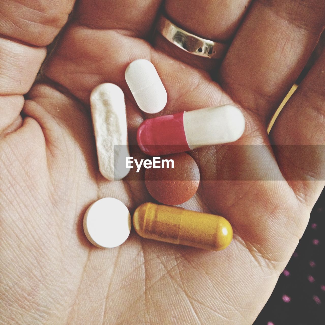 Cropped hand holding various pills and capsules