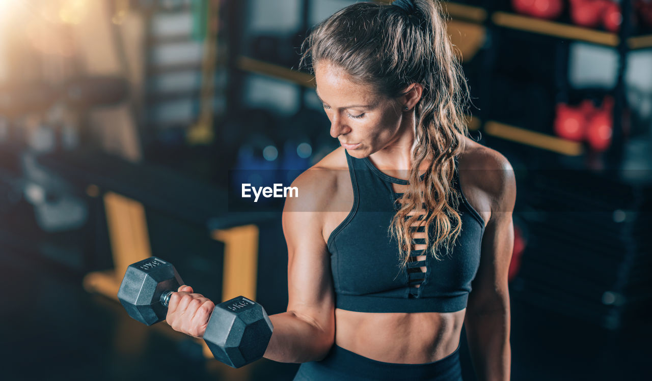 Female athlete doing biceps exercise with dumbbells. strength training.