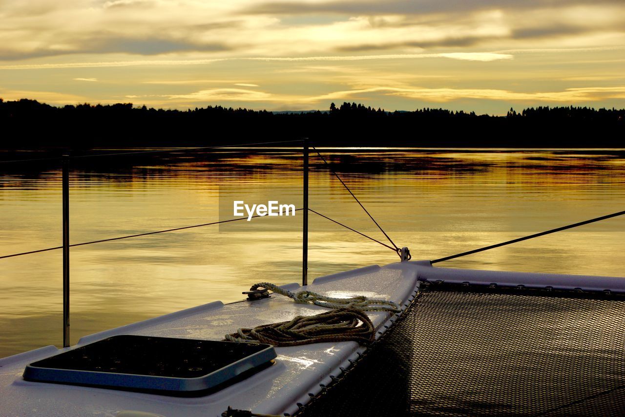 Boat in river against dramatic sky during sunset