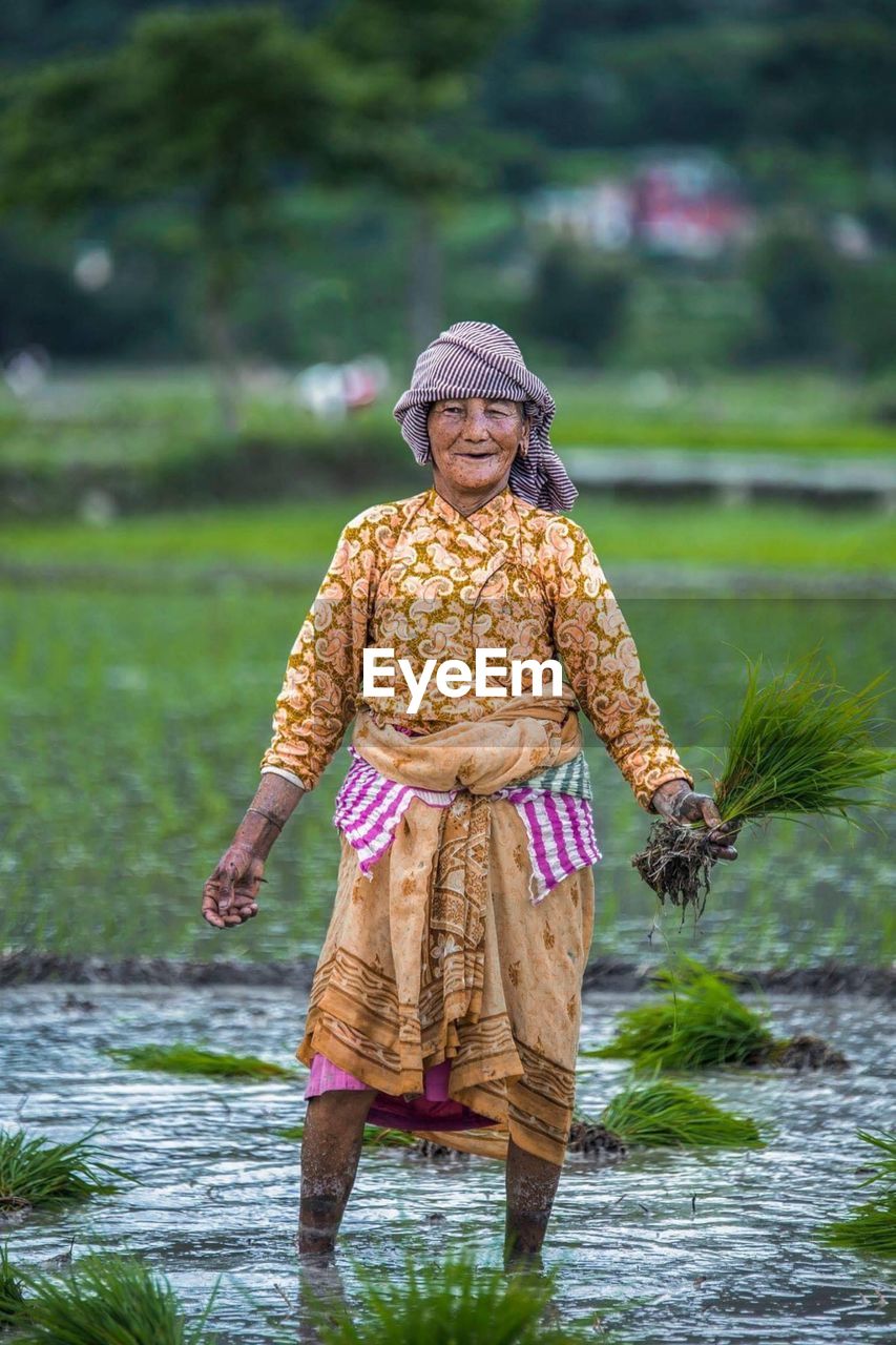 PORTRAIT OF A SMILING YOUNG WOMAN STANDING ON WATER