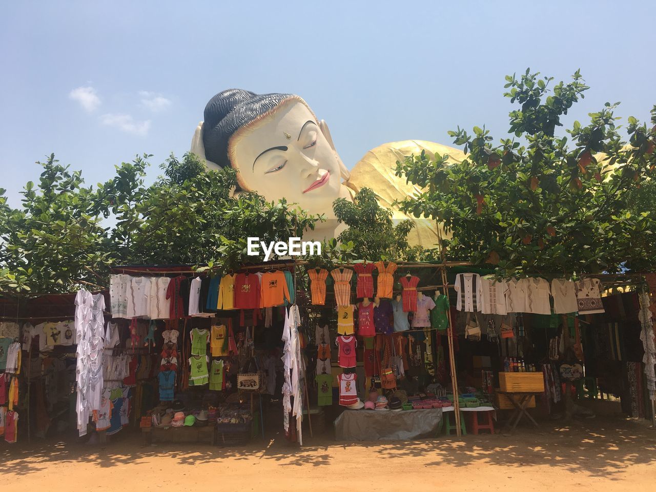 Clothes for sale at market stall against buddha statue