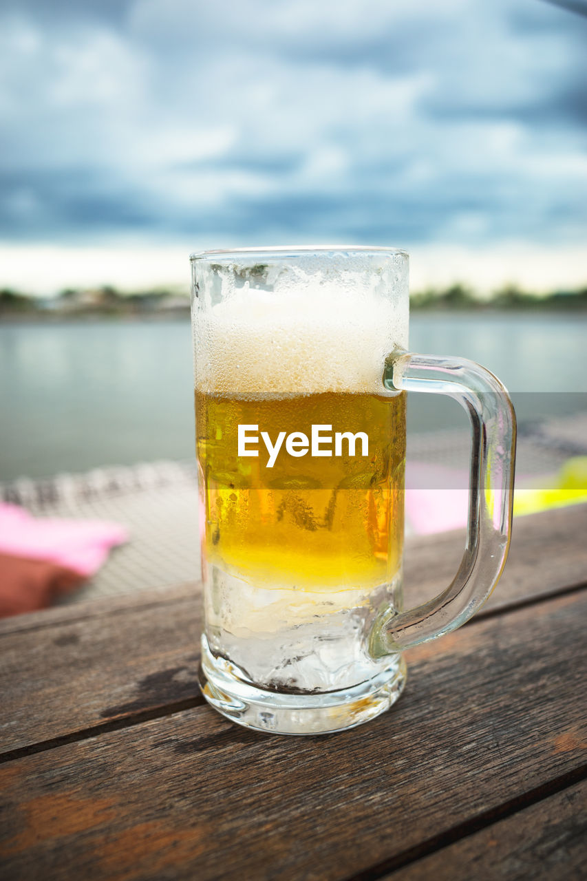 CLOSE-UP OF BEER GLASS ON TABLE AGAINST BLURRED BACKGROUND