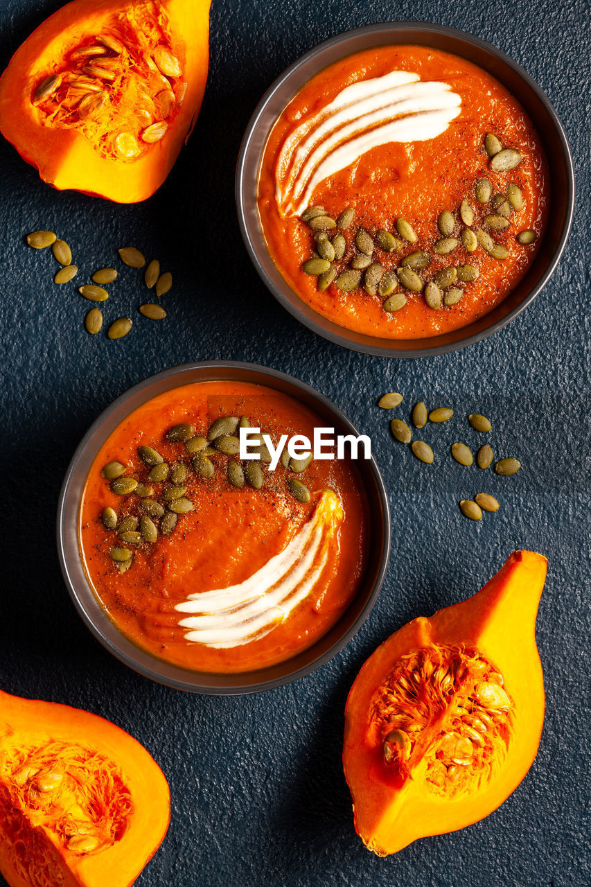 Plates with creamed pumpkin soup, pumpkin seeds and sliced pumpkins