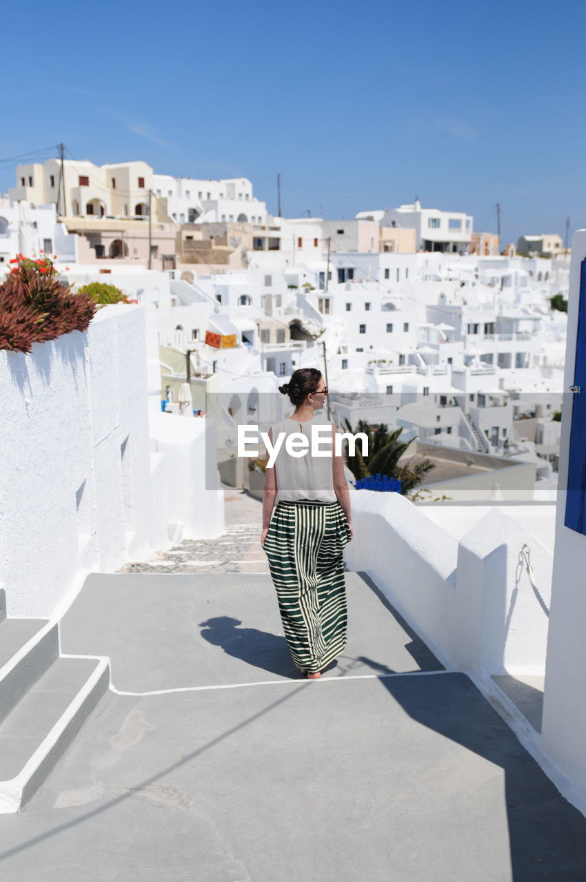 Rear view of woman on steps against buildings at santorini