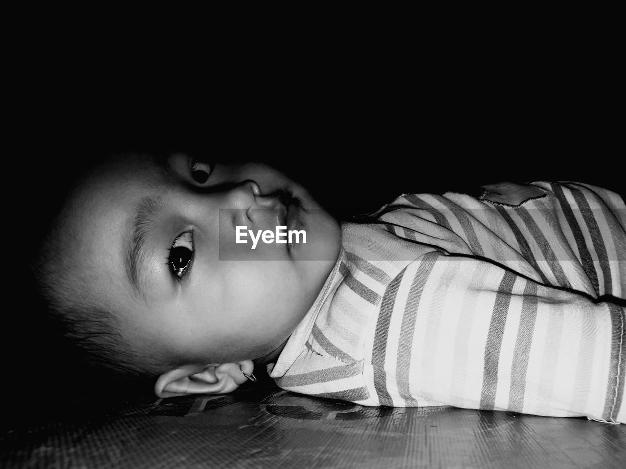 A potrait of a little girl lying on a ceramic floor mat