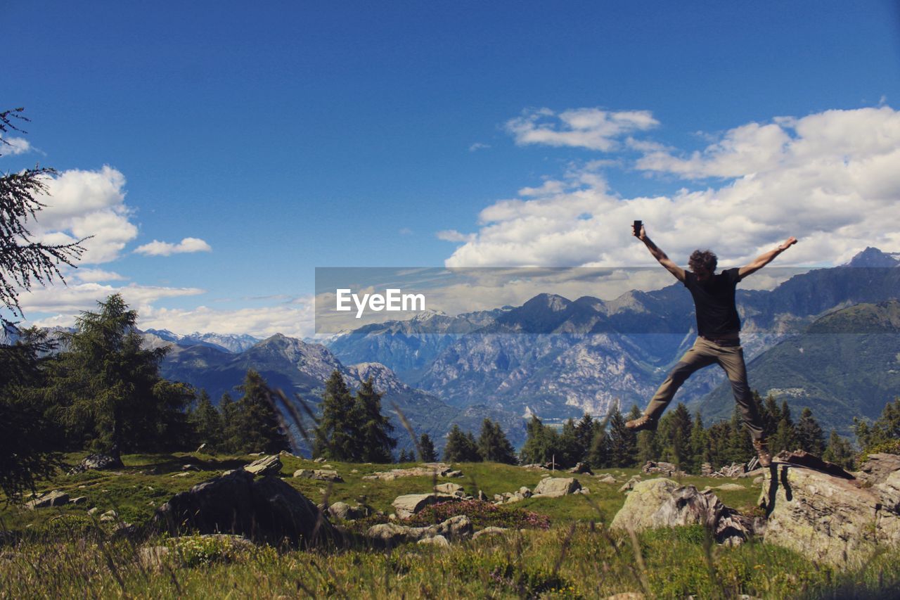 WOMAN WITH ARMS RAISED ON MOUNTAIN