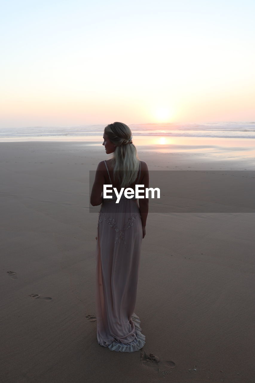 REAR VIEW OF WOMAN LOOKING AT SEA SHORE