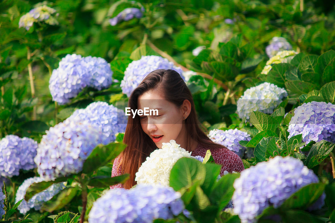 PORTRAIT OF BEAUTIFUL WOMAN WITH PINK FLOWERS IN GARDEN