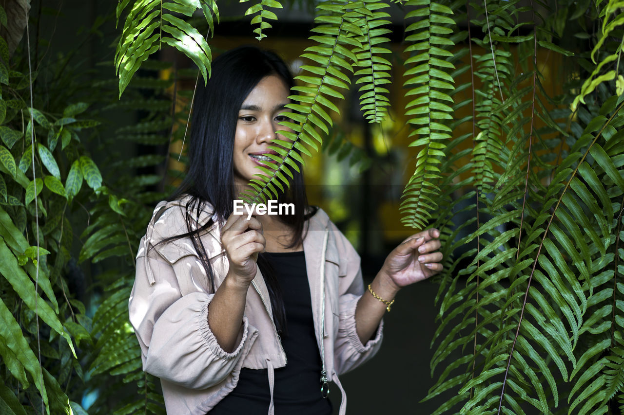 Young woman standing against plants