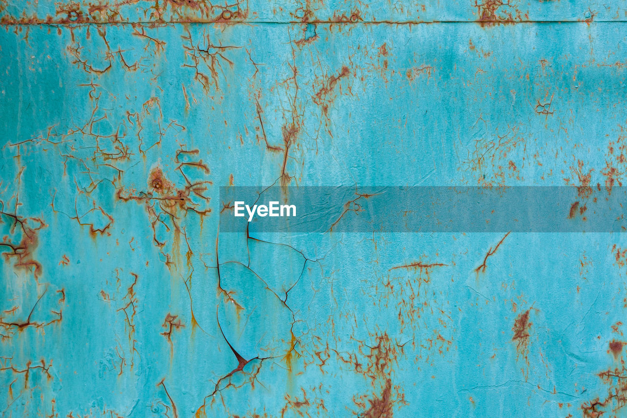 Turquoise painted flat steel sheet with cracks and rust stains
