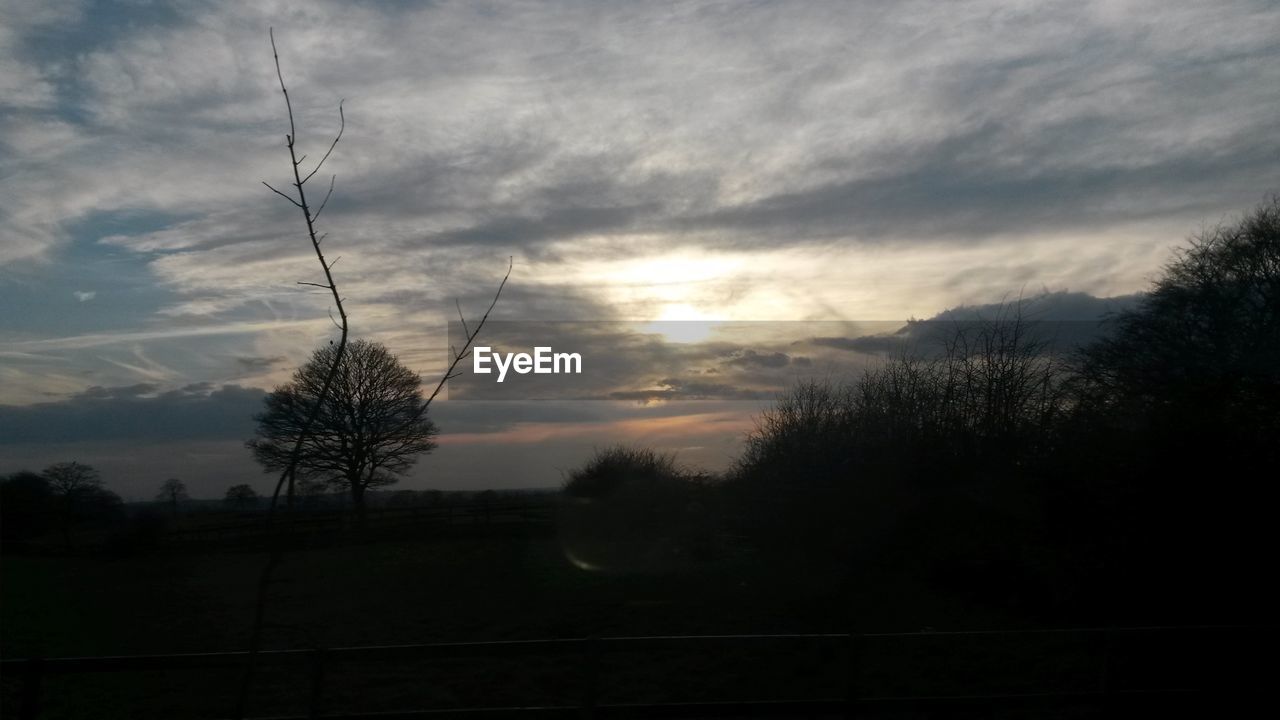 SILHOUETTE OF TREES ON LANDSCAPE AGAINST CLOUDY SKY