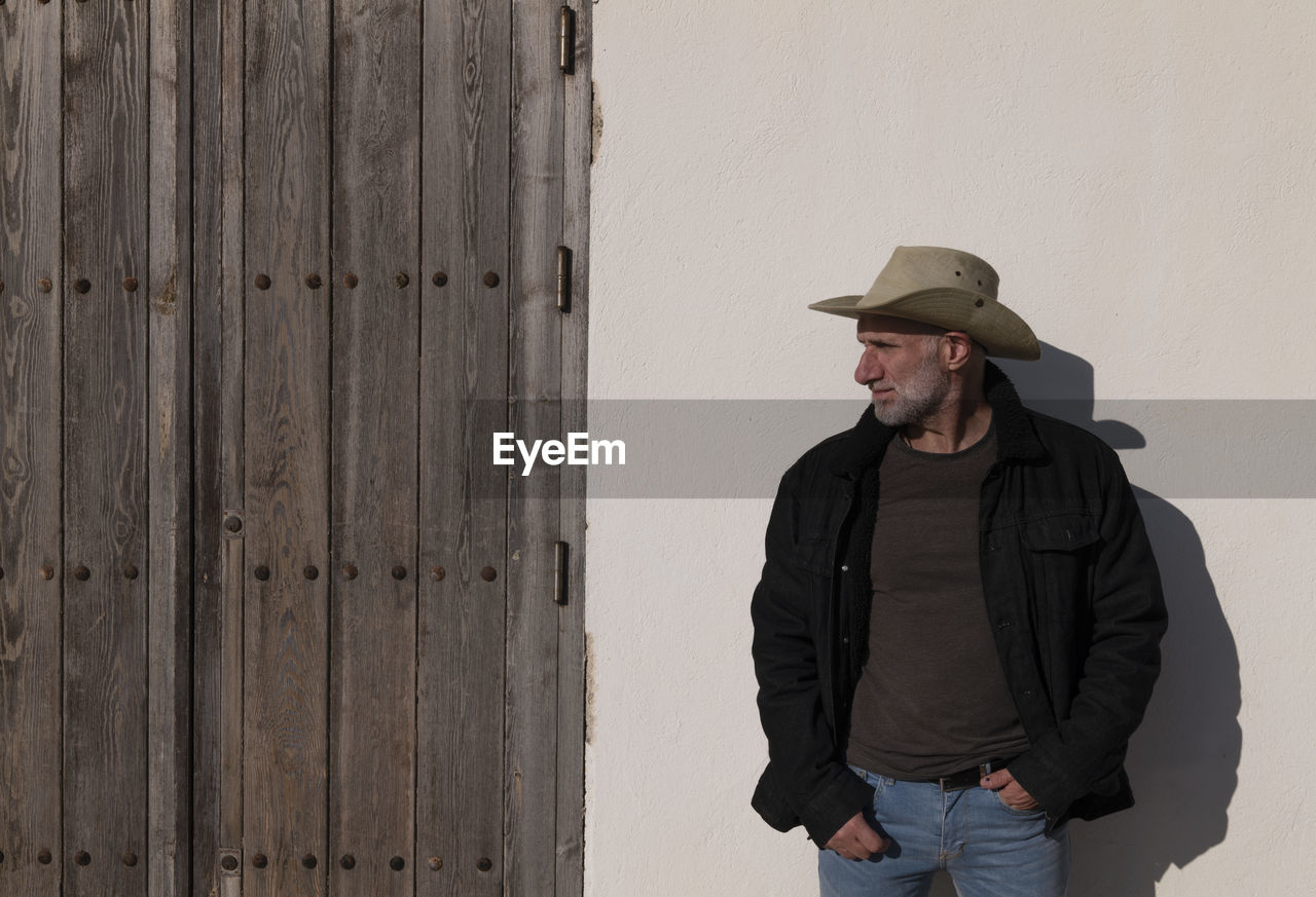 Portrait of adult man in cowboy hat and jeans against wall. almeria, spain