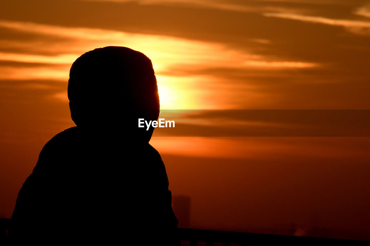 sunset, silhouette, sky, one person, cloud, orange color, backlighting, horizon, nature, beauty in nature, afterglow, sun, dawn, evening, tranquility, men, sunlight, dramatic sky, lifestyles, adult, outdoors, scenics - nature, child, tranquil scene, emotion, person, red sky at morning, water, back lit, dark