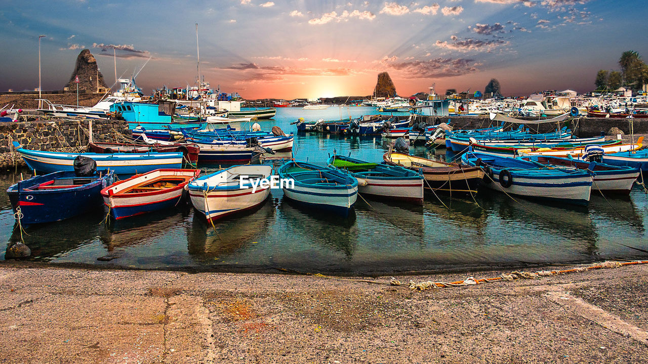 Boats moored at harbor during sunset