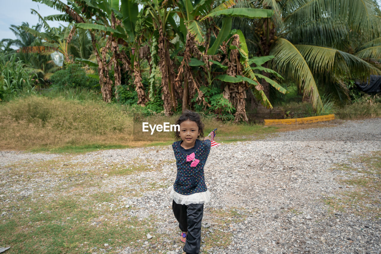 Portrait of girl holding malaysian flags on field 