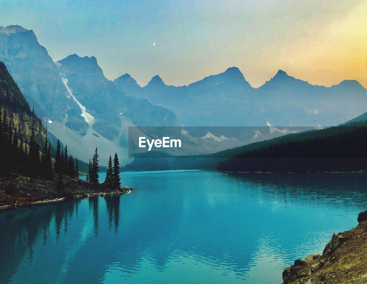 Scenic view of lake by mountains against sky