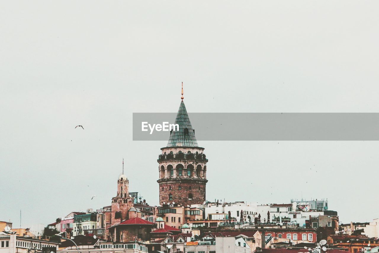 BIRDS FLYING OVER MOSQUE AGAINST SKY