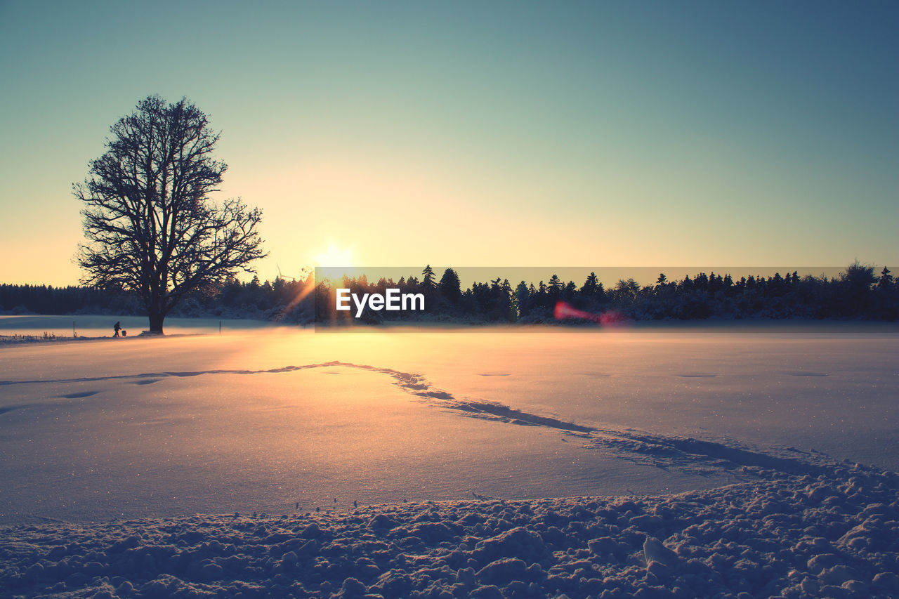 Scenic view of snow covered field against sky during sunset