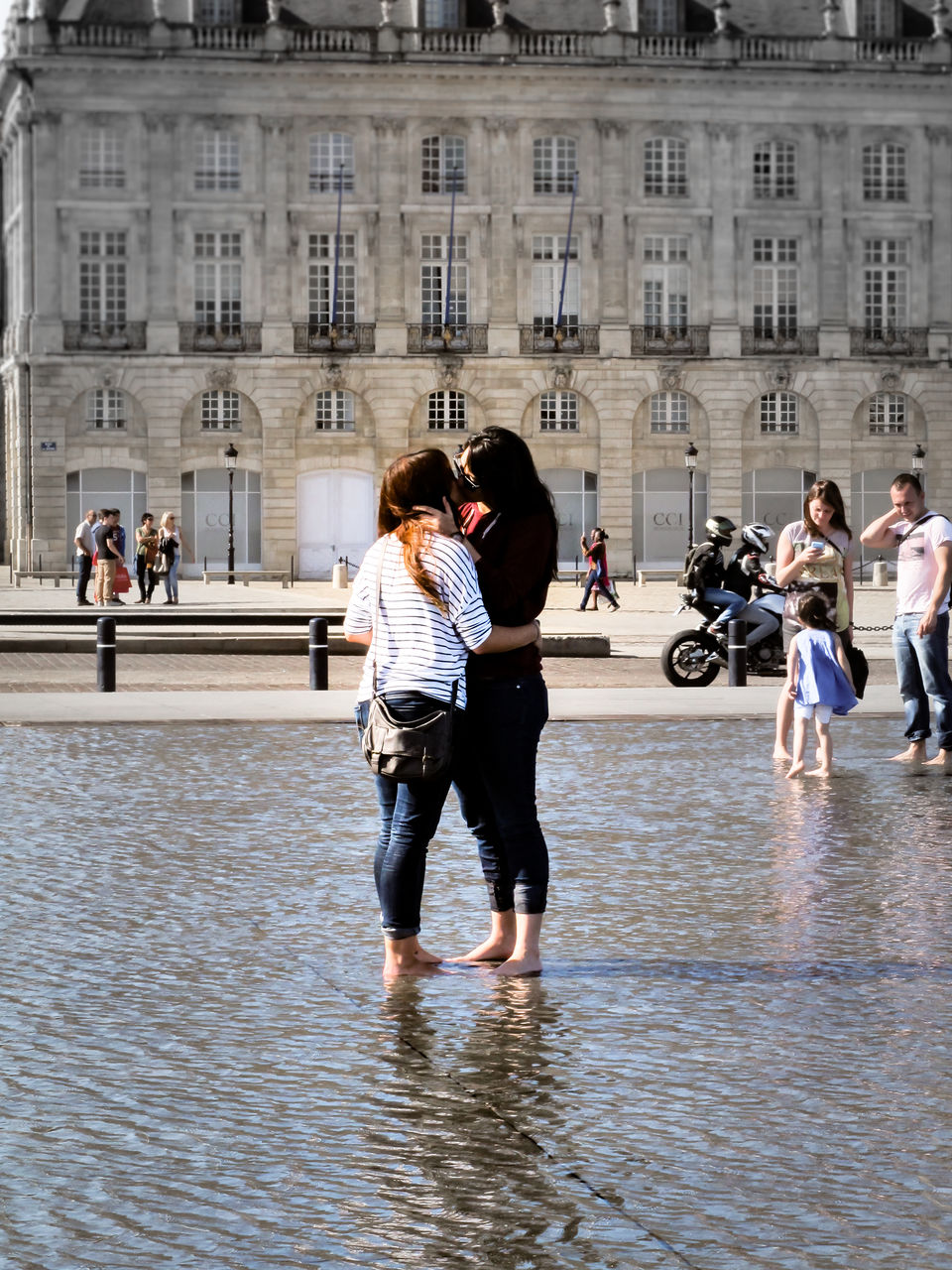 FULL LENGTH OF PEOPLE WALKING ON WET STREET AGAINST BUILDINGS IN CITY