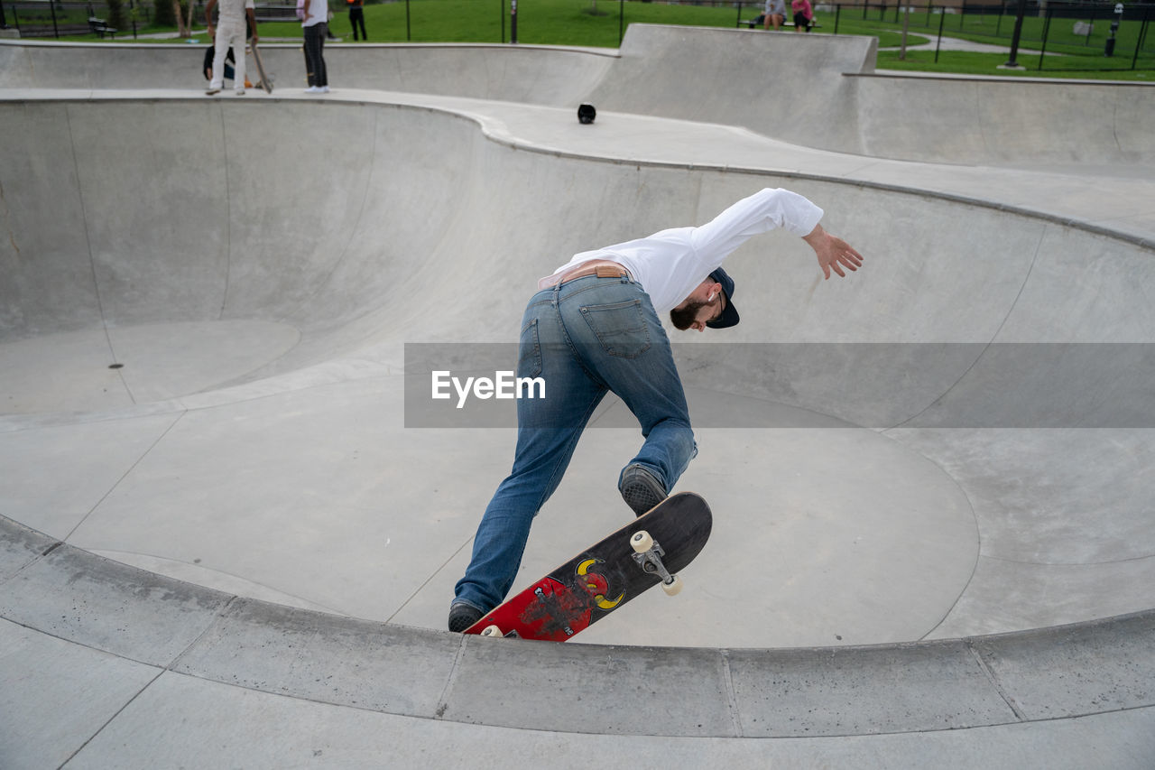 FULL LENGTH OF MAN SKATEBOARDING ON CONCRETE