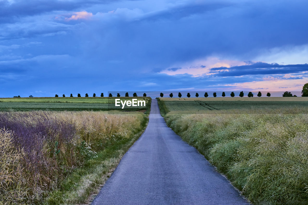 Road amidst field against sky