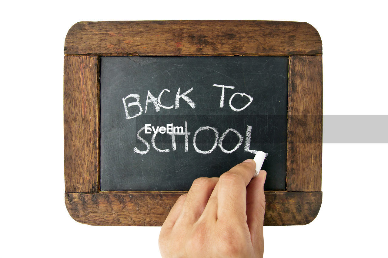 Cropped hand writing back to school on blackboard over white background