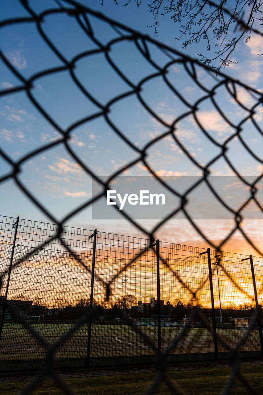 fence, chainlink fence, security, protection, sky, chain-link fencing, sunlight, light, sports, metal, nature, no people, wire fencing, wire, reflection, sunset, outdoor structure, outdoors, cloud, line, wire mesh, branch, architecture, iron, day