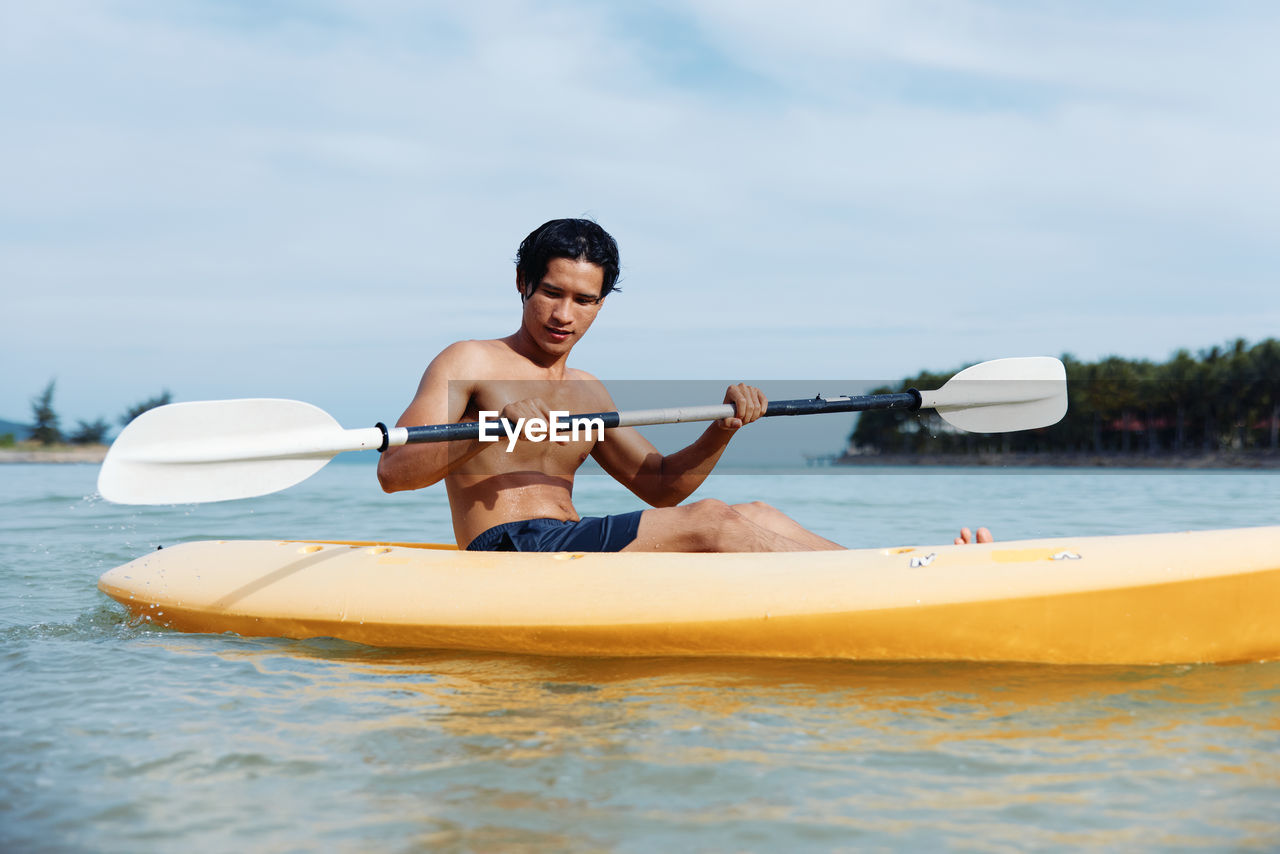 portrait of young man kayaking in sea