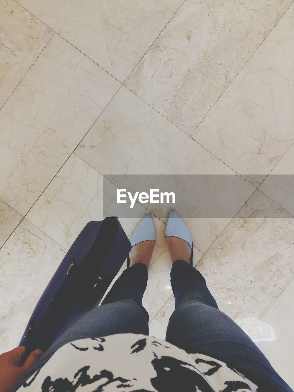 Low section of woman with shopping bag standing on tiled floor