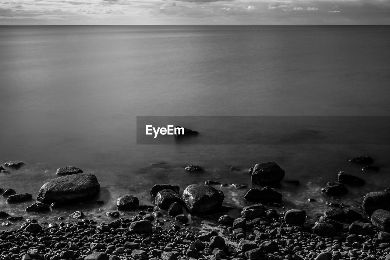 HIGH ANGLE VIEW OF ROCKS ON SHORE AGAINST SKY