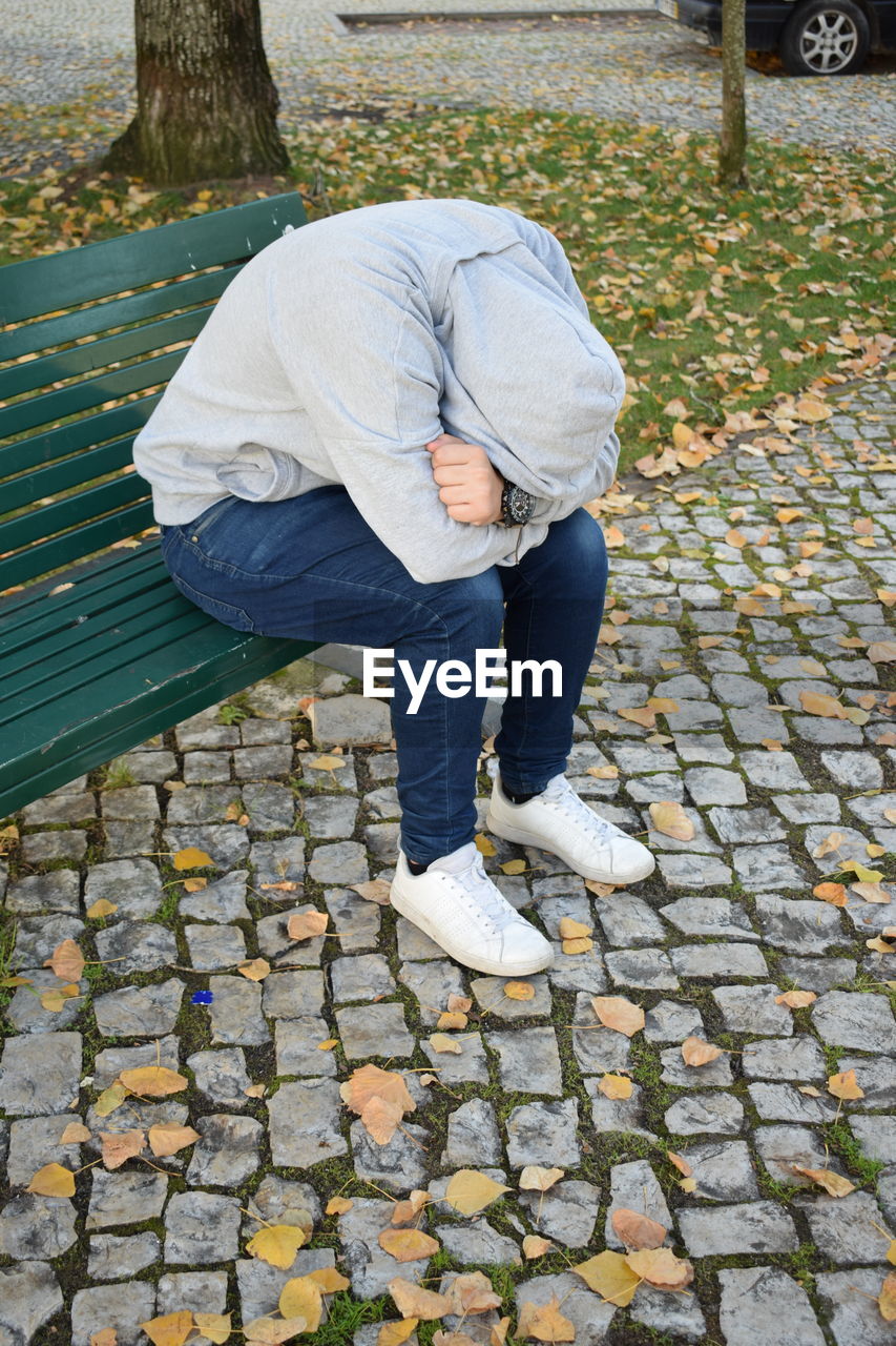 High angle view of sad man sitting on bench in park