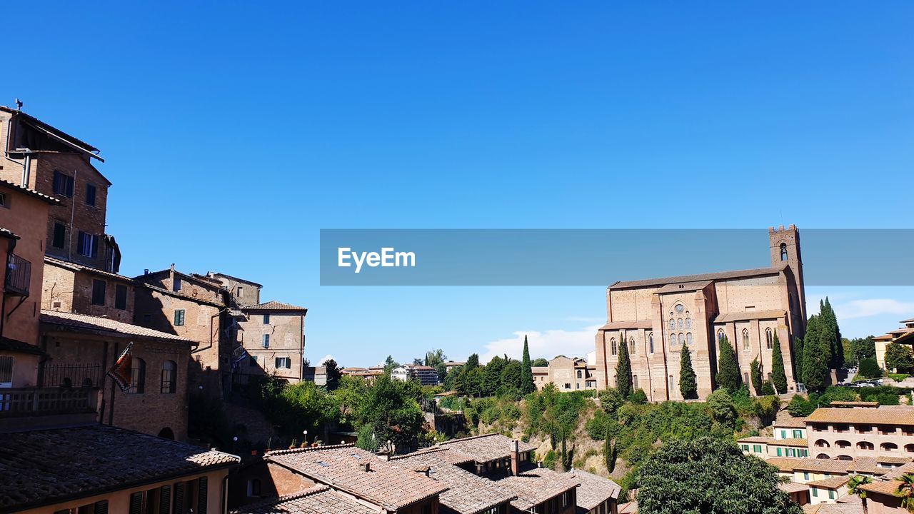 Buildings in city against clear blue sky