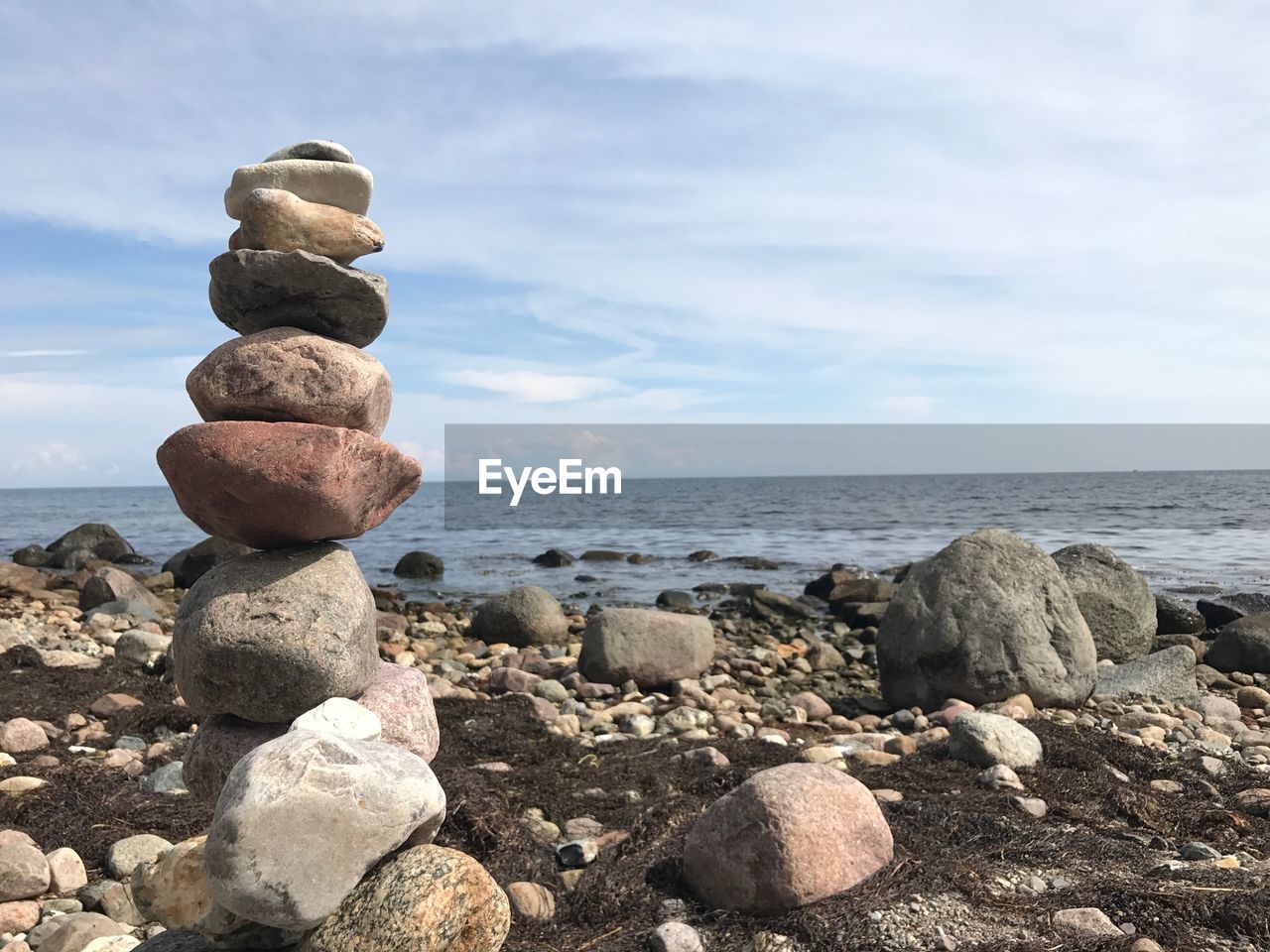 Stack of stones in sea against sky