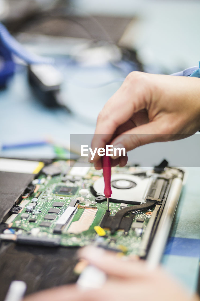 Cropped hand of technician repairing computer part on table