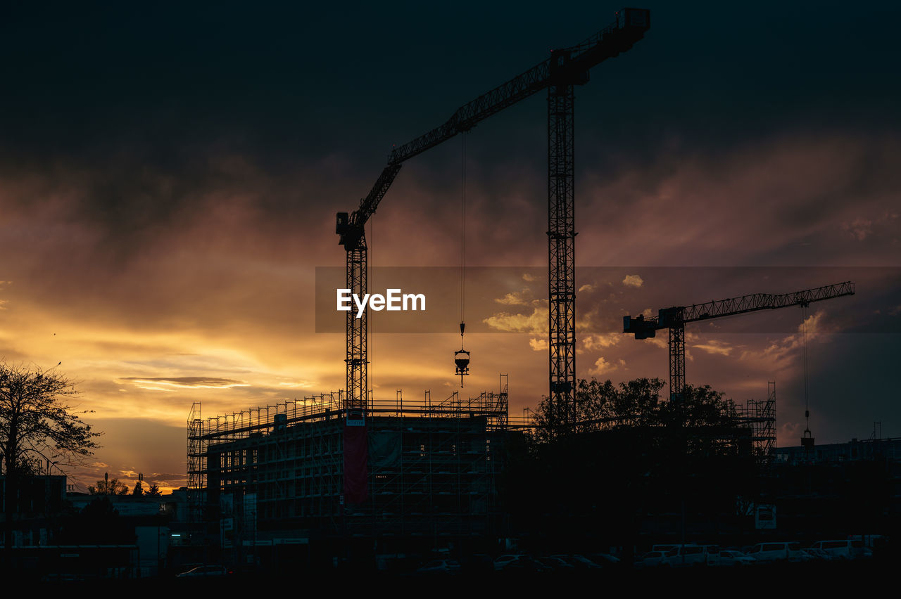 Cranes on a construction site at sunset