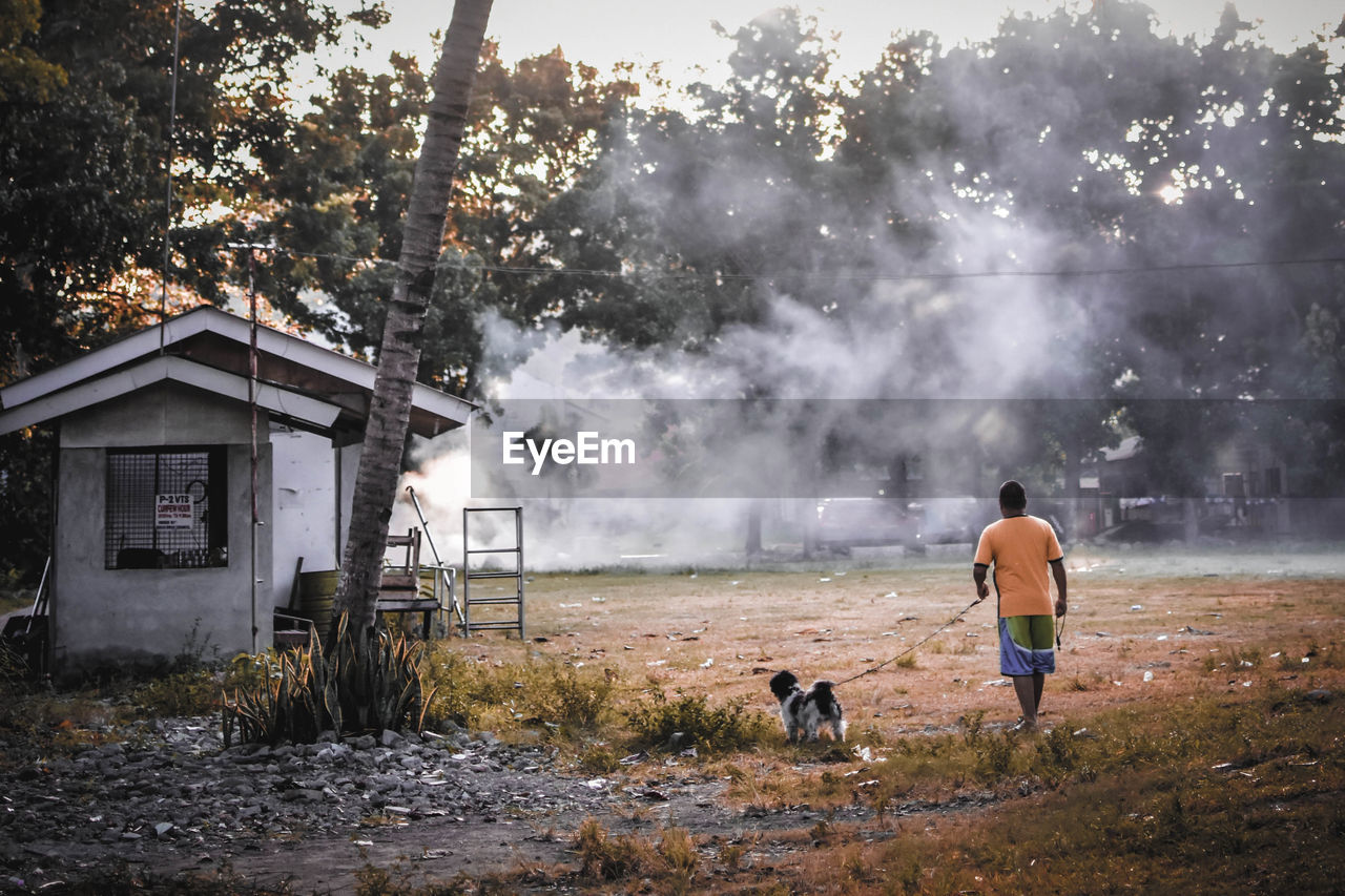 REAR VIEW OF MAN AND DOG ON STREET DURING FESTIVAL